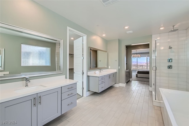 bathroom with a wealth of natural light, vanity, shower with separate bathtub, and a notable chandelier