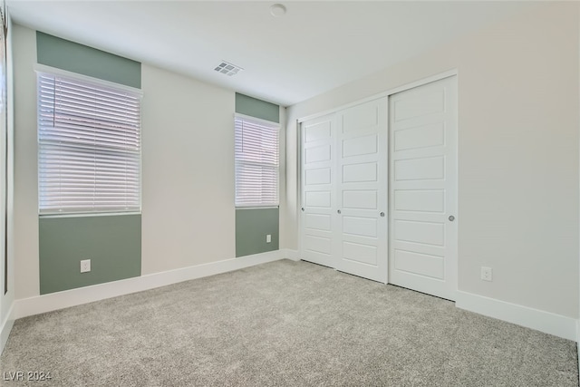 unfurnished bedroom with a closet and light colored carpet