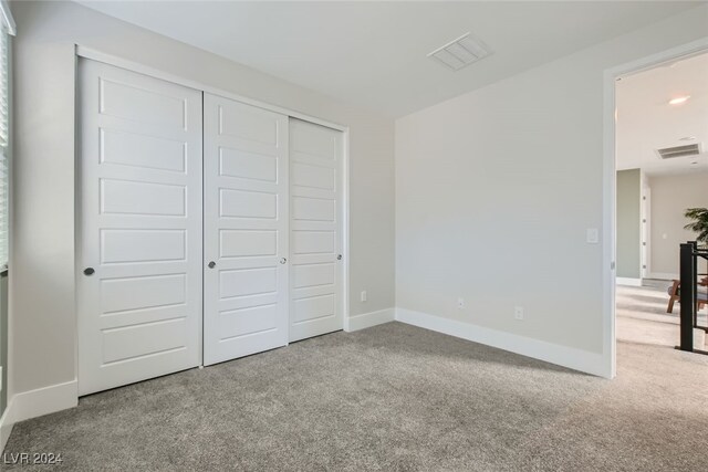 unfurnished bedroom featuring light carpet and a closet