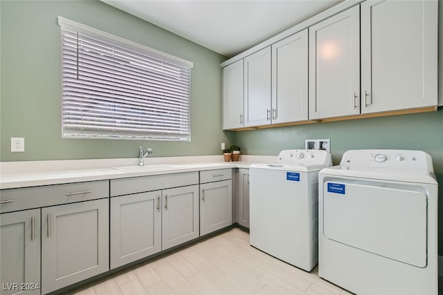 laundry area with sink, washer and clothes dryer, light hardwood / wood-style flooring, and cabinets