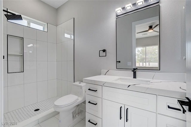 bathroom featuring vanity, a tile shower, toilet, and ceiling fan