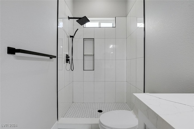 bathroom with toilet and tiled shower