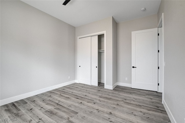 unfurnished bedroom featuring a closet, light hardwood / wood-style floors, and ceiling fan