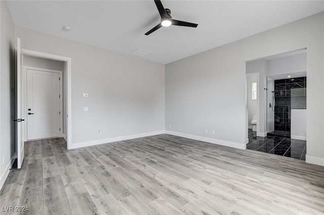 interior space with a walk in closet, ceiling fan, connected bathroom, wood-type flooring, and a closet