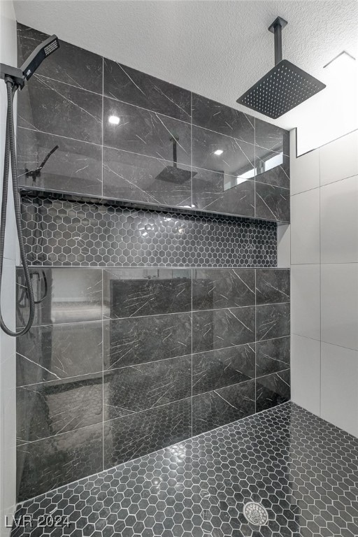 bathroom with a tile shower and a textured ceiling