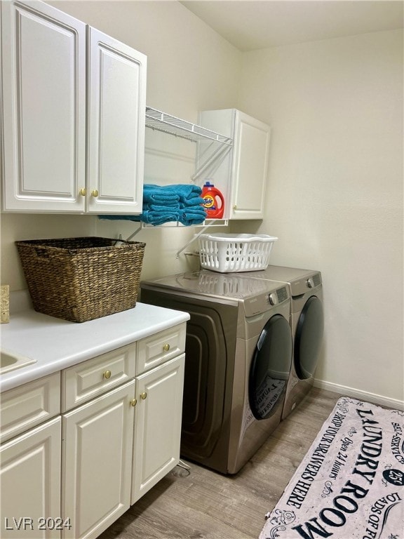 laundry room featuring cabinets, washer and dryer, and light hardwood / wood-style flooring