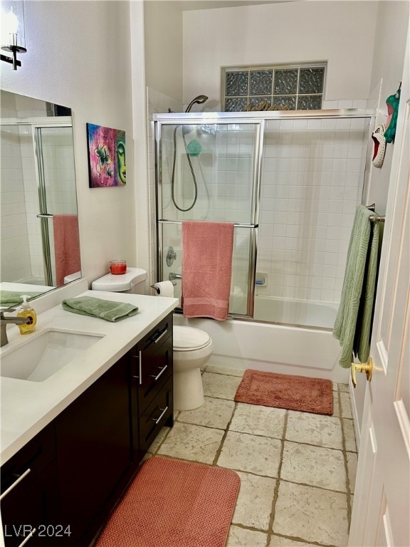 full bathroom with enclosed tub / shower combo, vanity, and toilet