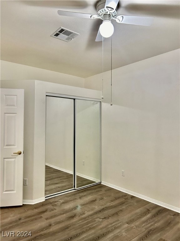 unfurnished bedroom with ceiling fan, a closet, and dark hardwood / wood-style flooring