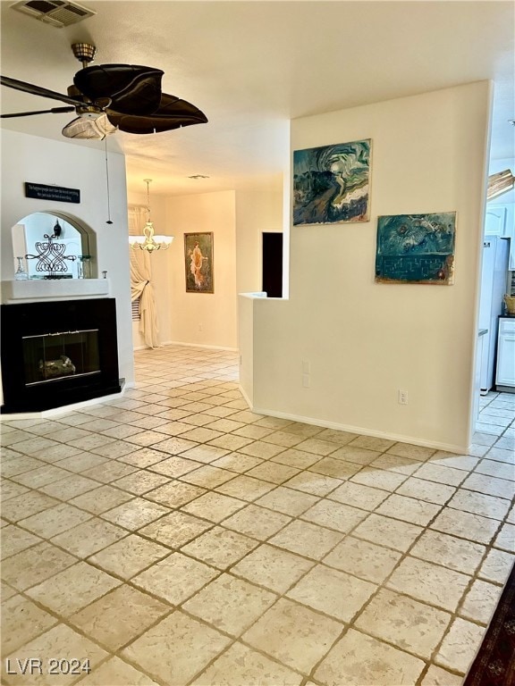 unfurnished living room featuring ceiling fan with notable chandelier