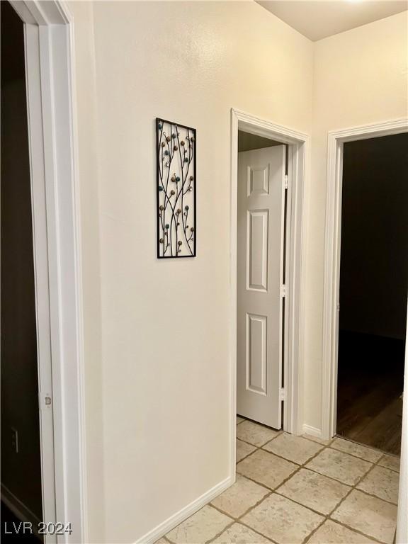 hallway featuring baseboards and light tile patterned floors