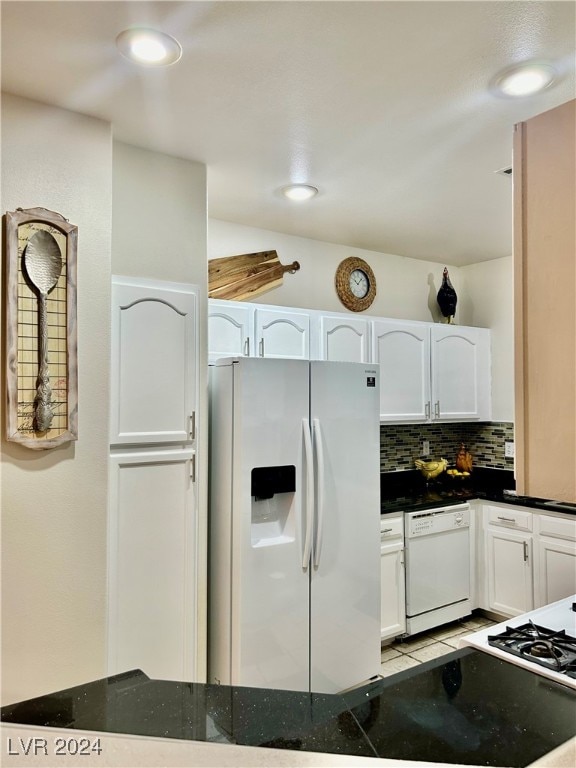 kitchen featuring white cabinets, white appliances, dark stone counters, and backsplash