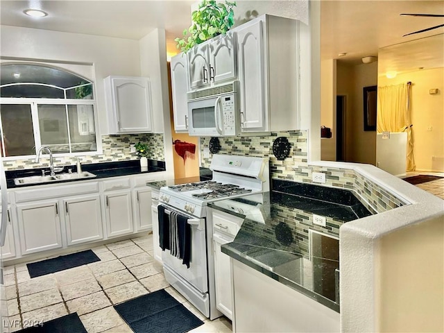 kitchen featuring white appliances, dark countertops, a sink, and tasteful backsplash
