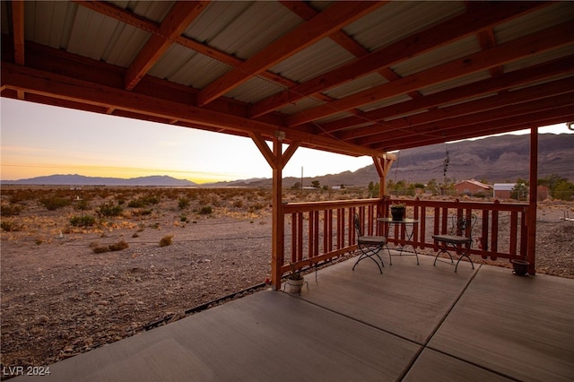 patio terrace at dusk featuring a deck with mountain view