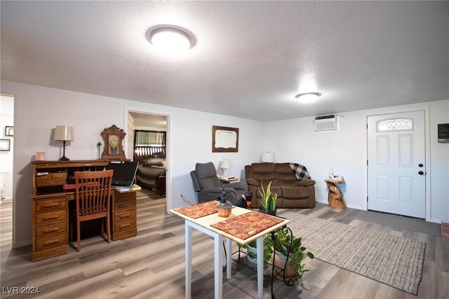 living room with hardwood / wood-style floors, a wall mounted AC, and a textured ceiling