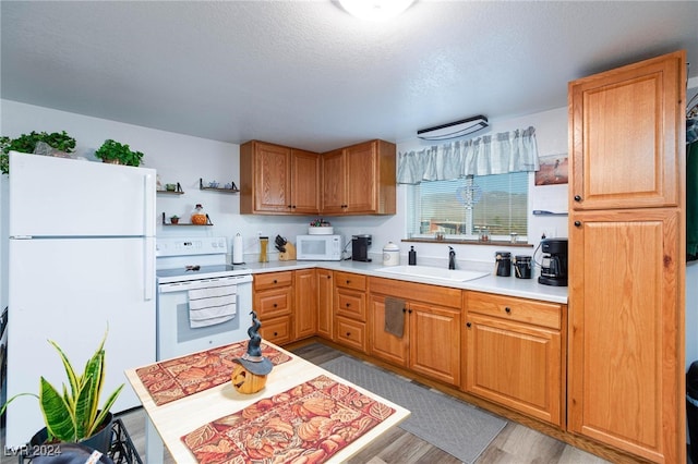 kitchen featuring light hardwood / wood-style floors, a textured ceiling, sink, and white appliances