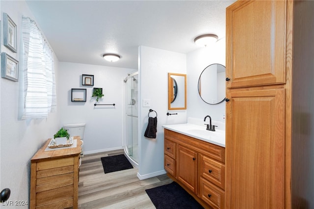 bathroom featuring vanity, toilet, hardwood / wood-style flooring, and a shower with shower door