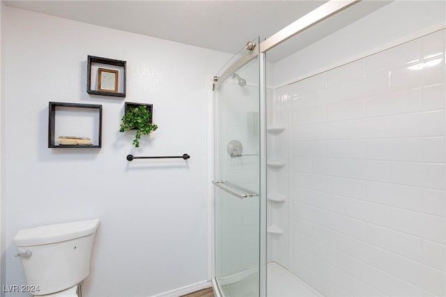 bathroom with a shower with door and toilet