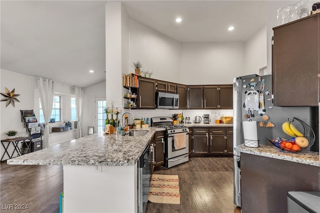 kitchen with appliances with stainless steel finishes, tasteful backsplash, dark brown cabinetry, sink, and high vaulted ceiling