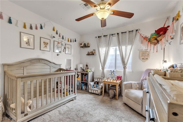 carpeted bedroom featuring a nursery area and ceiling fan