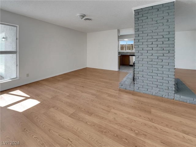 unfurnished living room with a healthy amount of sunlight, a textured ceiling, and light wood-type flooring