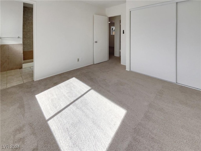 unfurnished bedroom with a closet and light colored carpet