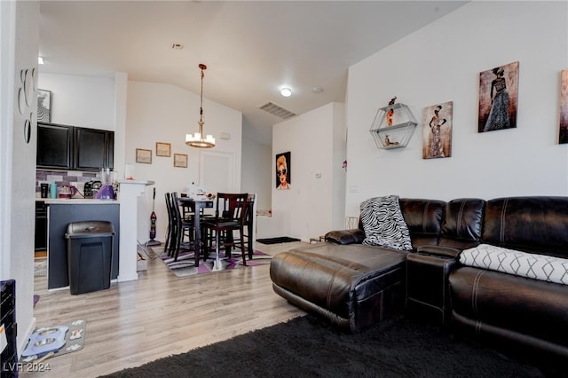 living room with light hardwood / wood-style floors, vaulted ceiling, and a chandelier