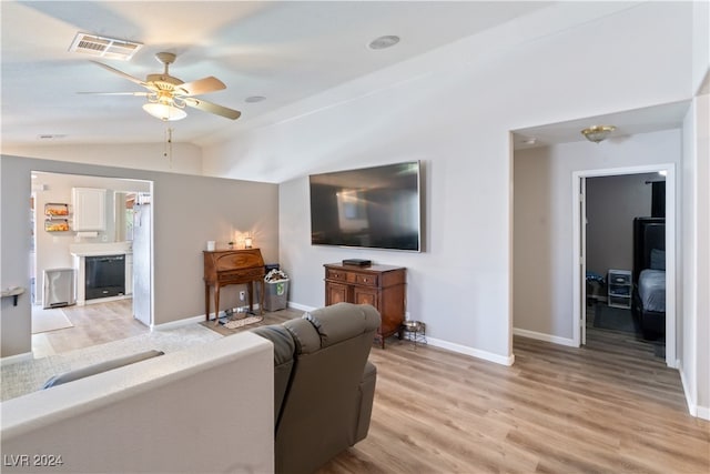 living room with ceiling fan, vaulted ceiling, and light wood-type flooring