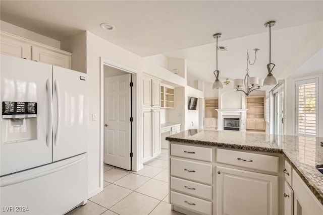 kitchen with white fridge with ice dispenser, light stone countertops, hanging light fixtures, white cabinetry, and light tile patterned floors