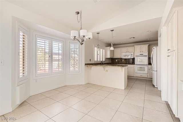 kitchen with kitchen peninsula, dark stone countertops, white appliances, and plenty of natural light