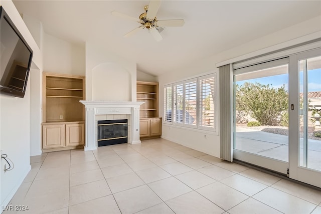 unfurnished living room featuring a tiled fireplace, light tile patterned floors, vaulted ceiling, and ceiling fan