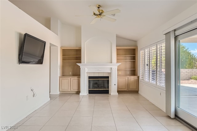 unfurnished living room featuring lofted ceiling, a tiled fireplace, light tile patterned floors, ceiling fan, and built in shelves