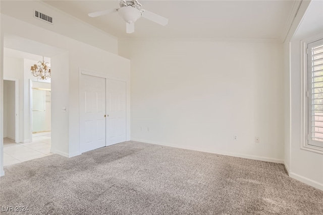 unfurnished bedroom with a closet, crown molding, light colored carpet, and ceiling fan with notable chandelier