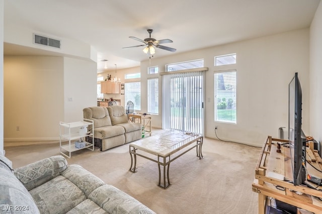 carpeted living room featuring ceiling fan with notable chandelier