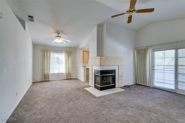 unfurnished living room featuring lofted ceiling, a healthy amount of sunlight, a tile fireplace, and ceiling fan