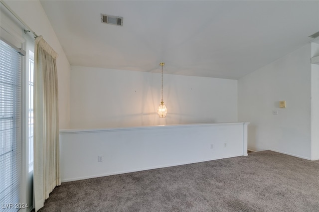 spare room featuring carpet, vaulted ceiling, and plenty of natural light