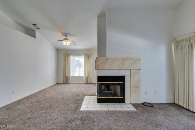 unfurnished living room featuring ceiling fan, a tile fireplace, and light colored carpet