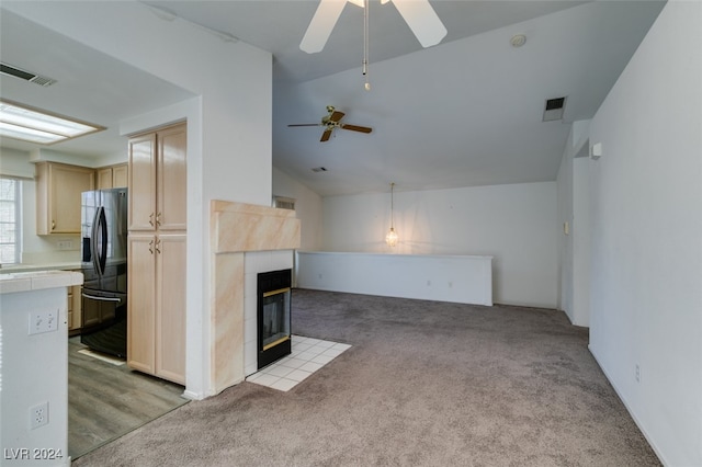 unfurnished living room with lofted ceiling, a tiled fireplace, light colored carpet, and ceiling fan