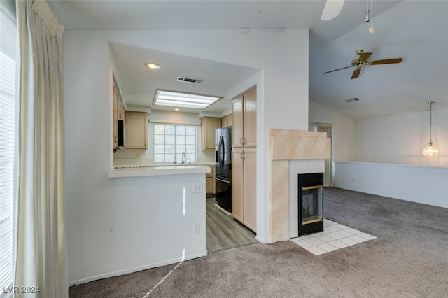 unfurnished living room with vaulted ceiling, a tiled fireplace, light colored carpet, and ceiling fan