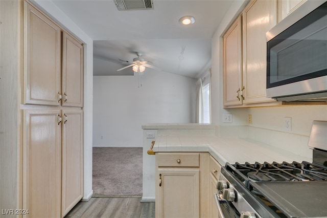 kitchen featuring light hardwood / wood-style flooring, stainless steel appliances, light brown cabinetry, and lofted ceiling