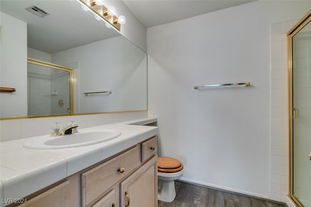 bathroom with a shower with door, vanity, hardwood / wood-style flooring, and toilet