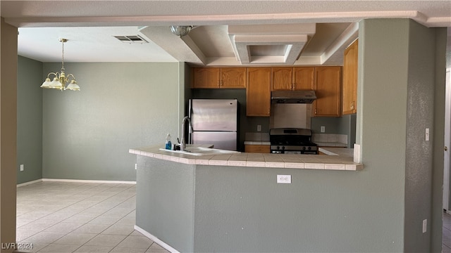 kitchen with appliances with stainless steel finishes, a chandelier, light tile patterned flooring, pendant lighting, and tile counters