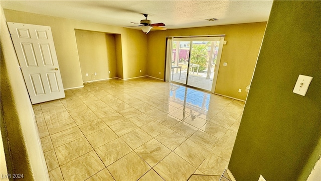 tiled empty room featuring a textured ceiling and ceiling fan