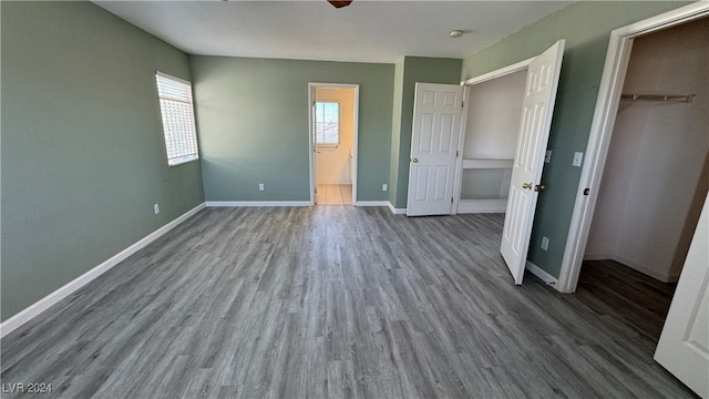 unfurnished bedroom with a closet, ceiling fan, a spacious closet, and hardwood / wood-style floors