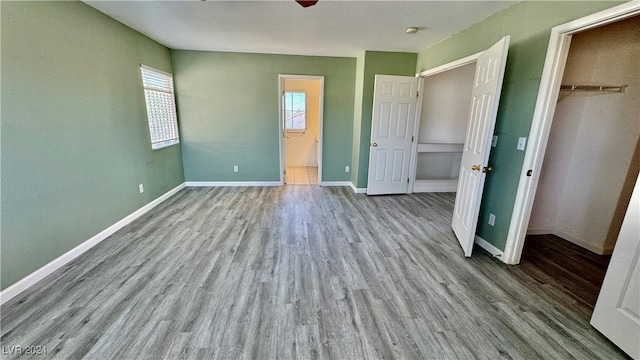 unfurnished bedroom featuring a closet, ceiling fan, a spacious closet, and light wood-type flooring