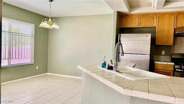 kitchen with an inviting chandelier, light tile patterned flooring, stainless steel appliances, range hood, and decorative light fixtures