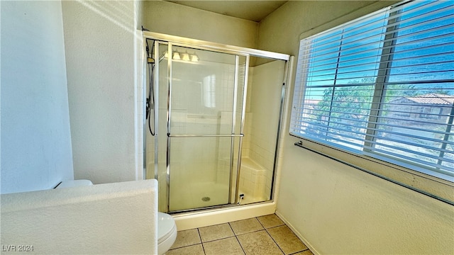 bathroom featuring a shower with shower door, toilet, and tile patterned flooring