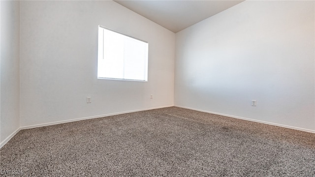 carpeted spare room with vaulted ceiling