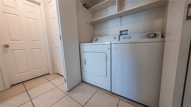 laundry area with washer and clothes dryer and light tile patterned floors