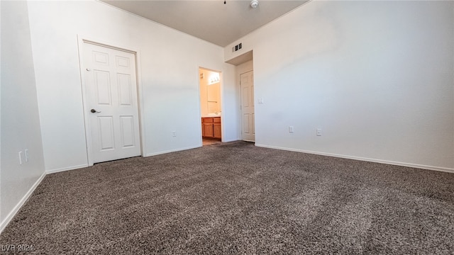 unfurnished bedroom with connected bathroom and dark colored carpet