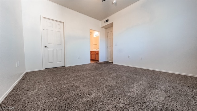 unfurnished bedroom with dark colored carpet and ensuite bath